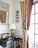 Curtain with tiebacks and side table with mirror in entrance hallway, Oxfordshire, England, UK