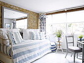 Striped light blue cover on day bed with large mirror in barn conversion, Oxfordshire, England, UK
