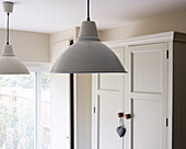 Muted metallic pendant shades with storage cupboard in North London home, England, UK