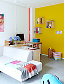 Home office with wall mounted shelves on yellow wall in Mattenbiesstraat family home, Netherlands