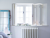 White window shutters above radiator in Devonshire country home UK