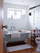 Freestanding roll-top bath under window in bathroom of Devonshire country home UK