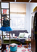 Tutu auf Leiter im Wohnzimmer mit Sofa am Fenster in Londoner Familienhaus England UK