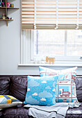 Patterned cushions on leather sofa at window of London family home England UK