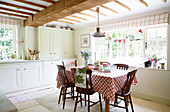 Red and white tablecloth on table in beamed Surrey farmhouse kitchen England UK