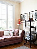 Pink leather sofa with antique display shelving in living room of London townhouse England UK