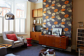 Retro style wallpaper and wooden sideboards in living room of family home in Margate Kent England UK