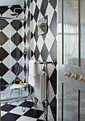 Door hooks and radiator with shower cubicle in chequered bathroom of Margate family home Kent England UK