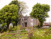 Rural farmhouse set in grounds with trees and gate in Derbyshire England UK