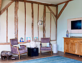 Anrichte aus Holz und Bogenlampe mit passenden Polsterstühlen im Wohnzimmer einer umgebauten Scheune in Nottinghamshire England UK