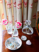 Cut tulips with perfume bottle and jewellery on wooden unit in bedroom of Nottinghamshire barn conversion England UK