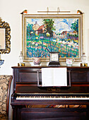 Gerahmtes Kunstwerk über einem Klavier mit Notenblättern in einem Landhaus in Oxfordshire England UK