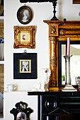 Gilt framed artwork and mirror with black mantlepiece in Oxfordshire country house England UK