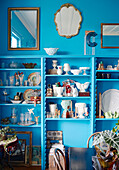 Vintage mirrors above collection of chinaware on bright blue shelving in Auckland home North Island New Zealand