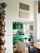Monkey sits on architectural pillar with elevated view of green fitted kitchen in Notting Hill home West London UK