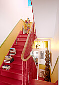 Bücherstapel auf einer rot gestrichenen Treppe in einem Haus in Notting Hill, West London, UK