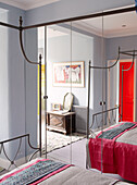 Reflection of four poster bed in mirrored wall of Notting Hill home West London UK