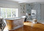 Freestanding metallic bath at window in with glass shower cubicle in Buckinghamshire home UK