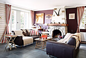 Pair of sofas in purple living room with exposed stone fireplace in Brittany guesthouse France