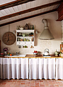 Extractor hood over kitchen worktop with wall mounted shelving in Brittany farmhouse France