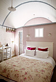 Pastel pink bedroom with floral quilt cover and desk in Brittany farmhouse France