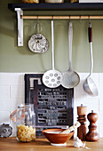 Kitchen utensils hang above typesetting board in Kent kitchen England UK