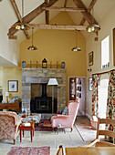 Brass pendant lights above living room with exposed stone fireplace in Hexham barn conversion Northumberland UK