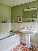 Tongue and groove bath with pedestal basin and tiled floor in green Hexham farmhouse bathroom Northumberland UK