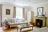 Lit woodburner with sofa and ottoman in living room of Northumbrian home England UK