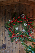 Pine cones and berries with feathers in wreath on wooden Oxfordshire front door England UK