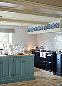 Dark blue Aga and decorative plates with light blue cupboards fitted to kitchen island in Oxfordshire home England UK
