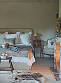 Gift wrapped presents on double bed with silver cover and antique armchair in Oxfordshire bedroom England UK