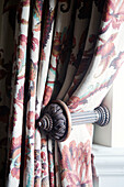 Floral curtains with wooden carved tie-back in County Durham home England UK