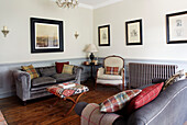 Grey sofas and framed artwork with patterned ottoman and armchair in County Durham home England UK