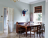 Wooden dining table and chair with blue animal head at window in County Durham home England UK