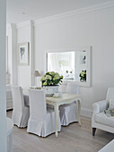 White slip covers on dining chairs at table with mirror in York townhouse England UK