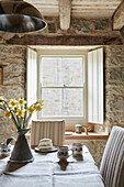 Narzissen in einem Krug auf einem Esstisch mit Biskuit und Tassen in einer denkmalgeschützten Tudor-Bastle Northumberland UK