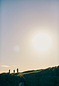Mann und Kinder spazieren an den Küstenklippen unter blauem Himmel in der Grafschaft Sligo in Connacht, Irland