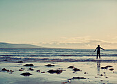 Boy standing at waters edge in wetsuit County Sligo in Connacht, Ireland
