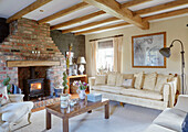 Lit woodburner in exposed brick fireplace with beamed ceiling in County Durham cottage, England, UK