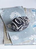 Decorated pebble paperweight on fabric sample in studio, UK