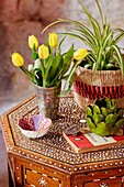 Yellow tulips and Spider plant with ornaments on inlaid Indian table in 18th century Northumbrian mill house, UK