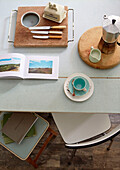 Open book and tableware on 1950s table with chair in Country Durham home, North East England