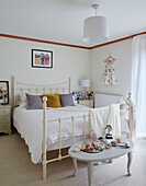 Yellow and lilac cushions on white metal framed double bed in Kent home, North East England, UK