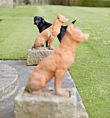 Black labrador with two dog statues in grounds of Capheaton Hall, Northumberland, UK