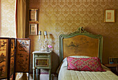 Handmade folding screen and antique bed with gold patterned wallpaper in 19th century Georgian townhouse in Talgarth, Mid Wales, UK