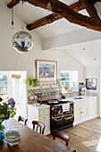 Discokugel hängt von der Balkendecke in offener Küche und Esszimmer in einem Haus in Yorkshire, England, UK