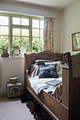 Antique wooden bed below window in Powys cottage, Wales, UK