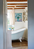 Light blue slipper bath below beamed ceiling in Warwickshire farmhouse, UK