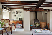 Woodburner and sideboard under beamed ceiling in Oxfordshire cottage, England, UK